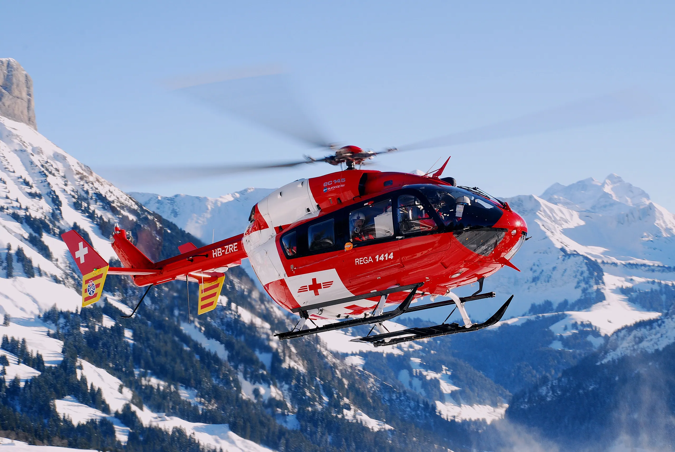 Airbus H145 helicopter flying over snow-capped mountains
