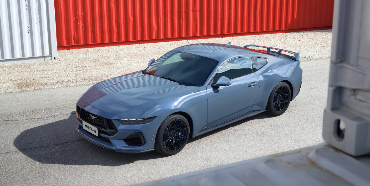 Ford Mustang GT in Vapor Blue parked by shipping containers